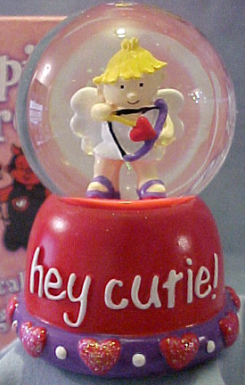 Gund Valentine's Day Musical Water Globe Cupid
- Plays "Love Me Tender"
- Comes boxed in a decorated gift box (see background of picture)
- Small red hearts and glitter in globe. On the base it reads "Hey Cutie!" 
- Has hearts and beads around bottom of base. He is holding the bow and arrow ready to shoot for LOVE!
