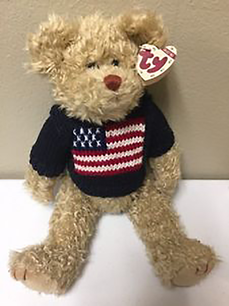TY Attic Treasure Grant Patriotic Teddy Bear
- introduced on 1/1/98 and retired on 8/30/99
- Fully jointed plush tan teddy bear
- He is wearing a dark blue sweater with an American flag on the front
- Designed by Ty Warner